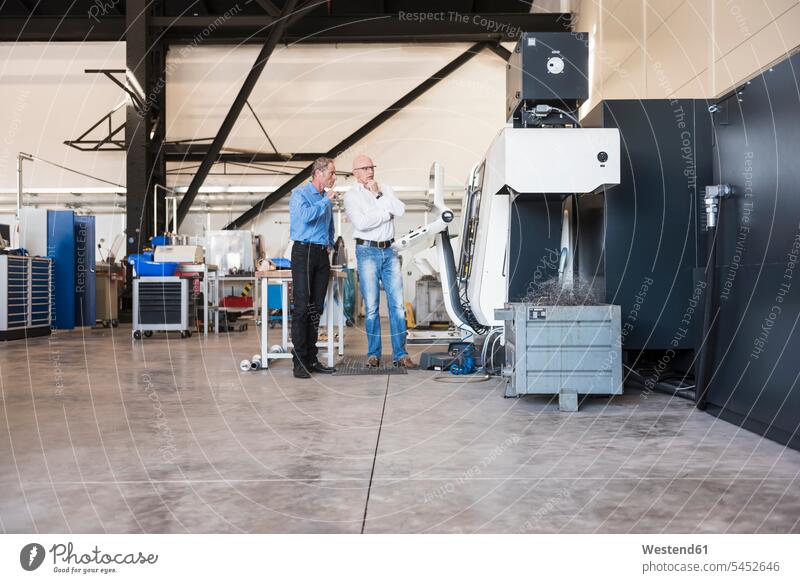 Zwei Männer sprechen an einer Maschine in der Fabrikhalle Maschinen Fabriken Geschäftsmann Businessmann Businessmänner Geschäftsmänner Gerät Geräte