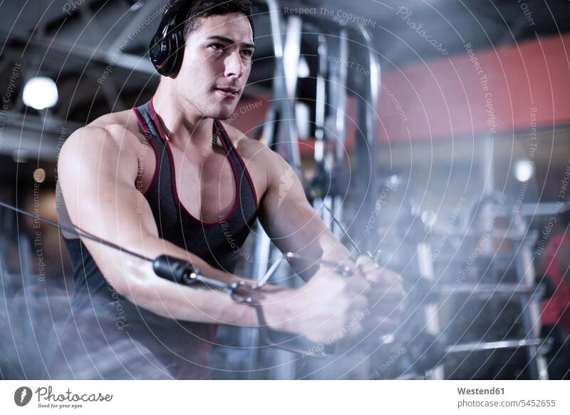 Fokussierter Mann benutzt Kabel-Trainingsgeräte im Fitnessstudio trainieren Männer männlich Fitnessclubs Fitnessstudios Turnhalle Erwachsener erwachsen Mensch
