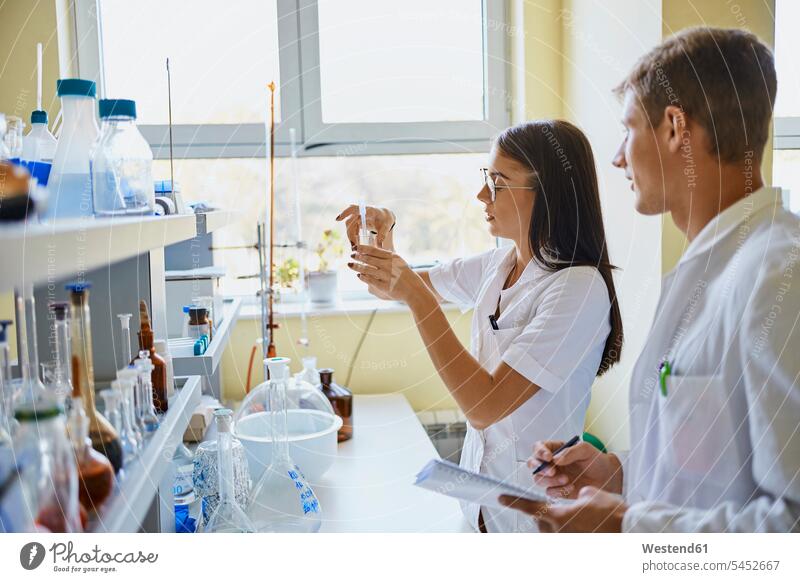 Junger Mann und Frau arbeiten gemeinsam im Labor Gemeinsam Erwachsener Mensch Arbeitsplatz pipettieren Zusammenarbeit Laborkittel Kurs Fenster Innenaufnahme