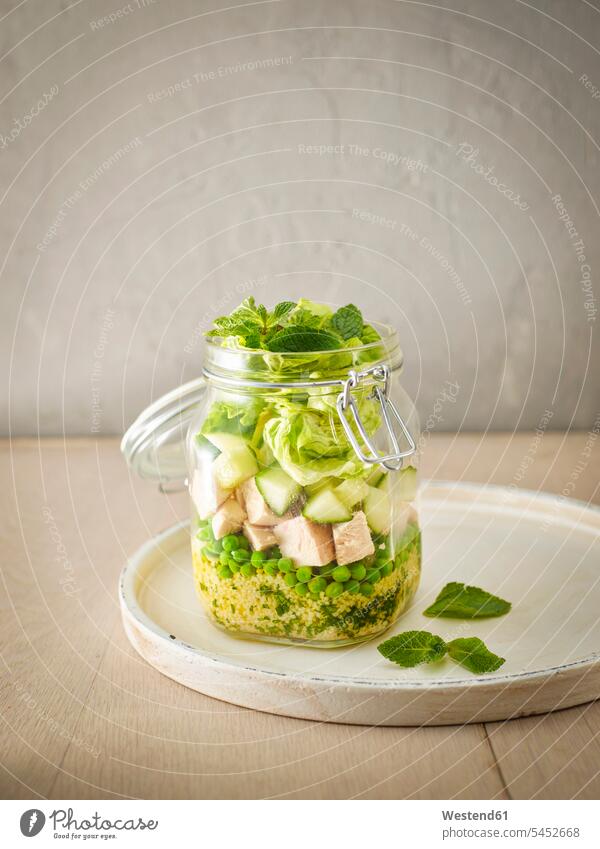 Einmachglas mit Couscous-Salat mit Erbsen, Gurken und gewürfeltem gekochtem Huhn Essen zum Mitnehmen Kuskus Marinade Pfefferminze Einweckglas Vorratsglas