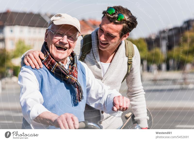 Glücklicher älterer Mann mit erwachsenem Enkel in der Stadt in Bewegung glücklich glücklich sein glücklichsein lachen Enkelsöhne Enkelsohn Großvater Opa