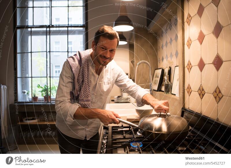 Porträt eines lächelnden Mannes beim Kochen zu Hause Küche Küchen kochen Männer männlich Erwachsener erwachsen Mensch Menschen Leute People Personen Gasherd