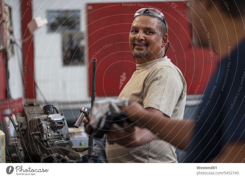 Zwei Mechaniker arbeiten in der Werkstatt am Motorradmotor Arbeit Motorräder Kollegen Arbeitskollegen Monteur reparieren Reparatur Kraftfahrzeug Verkehrsmittel