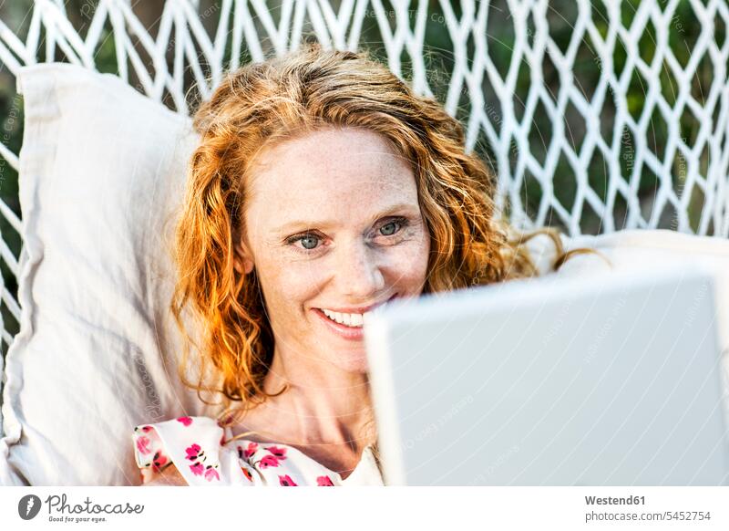 Lächelnde Frau mit Tablette in Hängematte liegend weiblich Frauen entspannt entspanntheit relaxt lächeln Tablet Computer Tablet-PC Tablet PC iPad