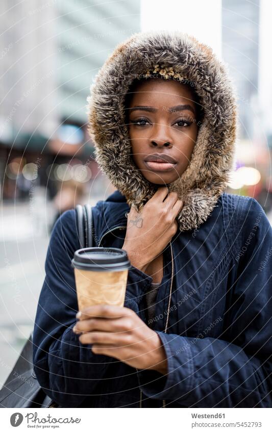 Porträt einer modischen jungen Frau mit Kaffee zum Mitnehmen in Kapuzenjacke ernst Ernst Ernsthaftigkeit ernsthaft Kapuzenjacken Coffee to go zum mitnehmen