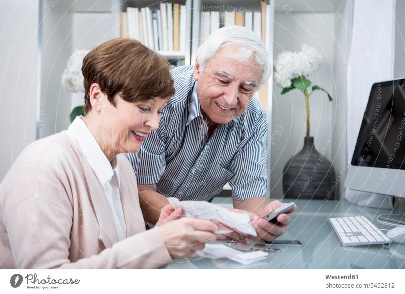 Älteres Ehepaar mit Rechnungen und Taschenrechner zur Kontrolle ihrer Ausgaben Kosten Online-Shopping Online Shopping Internet-Shopping Onlineshopping Senioren