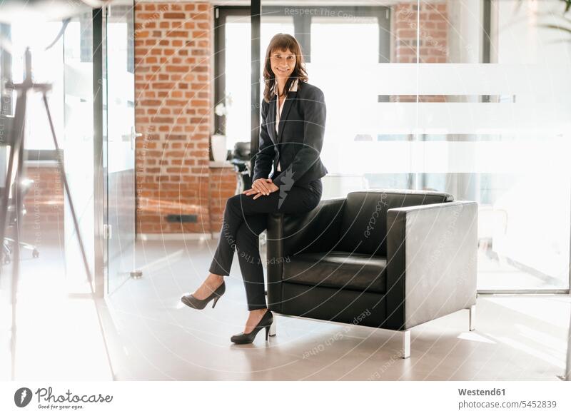Erfolgreiche Geschäftsfrau auf Sessel sitzend Kompetenz kompetent Büro Office Büros glücklich Glück glücklich sein glücklichsein Geschäftsfrauen Businesswomen