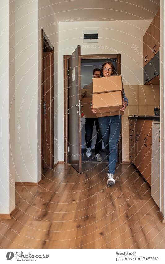 Junge Frauen und Männer tragen Pappkartons in einen Raum Karton Kartons Zimmer Räume transportieren Mann männlich Freunde Erwachsener erwachsen Mensch Menschen
