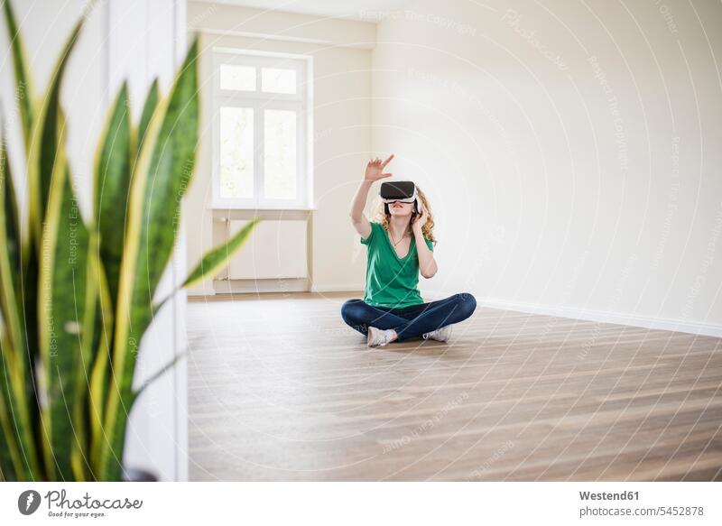 Frau in leerer Wohnung mit VR-Brille wohnen Wohnungen Virtual Reality Brille Virtual-Reality-Brille Virtual Reality-Brille VR Brille weiblich Frauen Wohnen