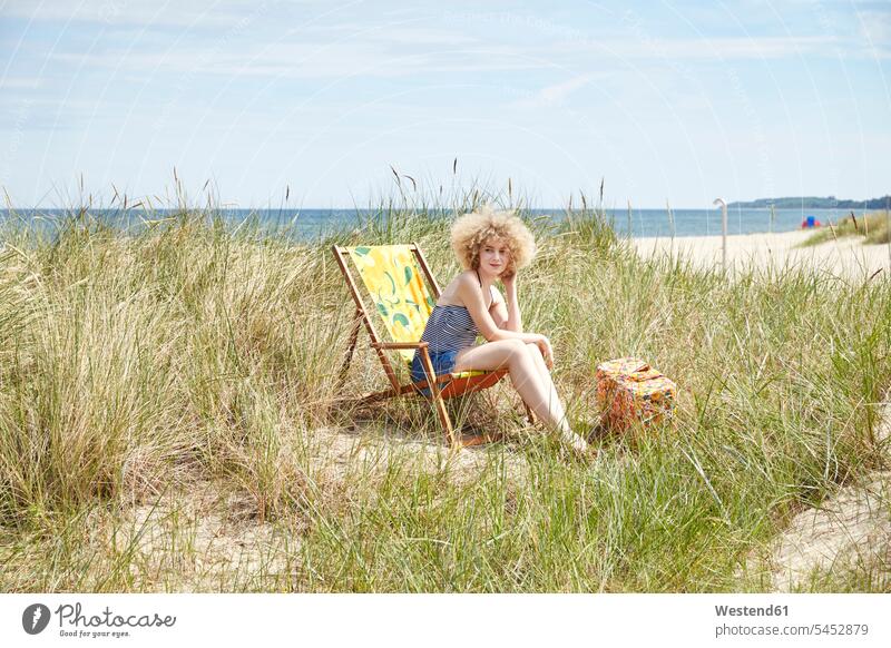 Junge Frau sitzt im Strandkorb in den Dünen und beobachtet etwas weiblich Frauen Liegestuhl Strandstuhl Stranddüne Strandduene Strandduenen Stranddünen