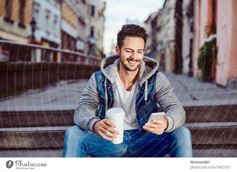 Mann mit Kaffee sitzt auf einer Treppe in der Stadt und telefoniert Männer männlich Handy Mobiltelefon Handies Handys Mobiltelefone sitzen sitzend lächeln