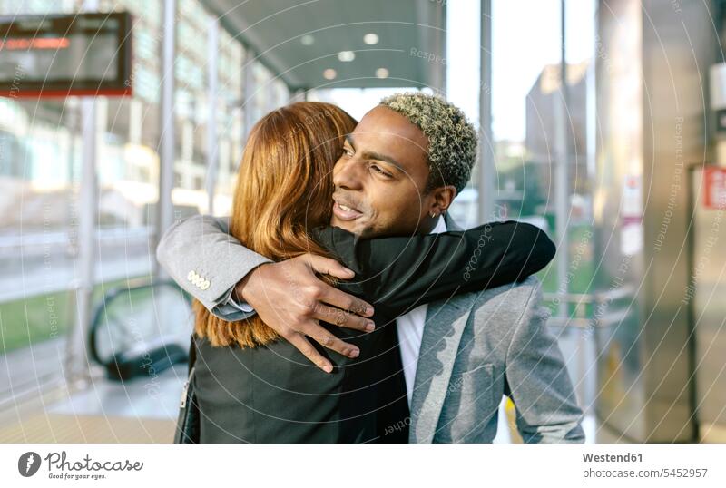 Junger Geschäftsmann und junge Geschäftsfrau umarmen sich in der U-Bahn-Station Geschäftsleute Geschäftspersonen Abschied Abschied nehmen Lebewohl Abschiede