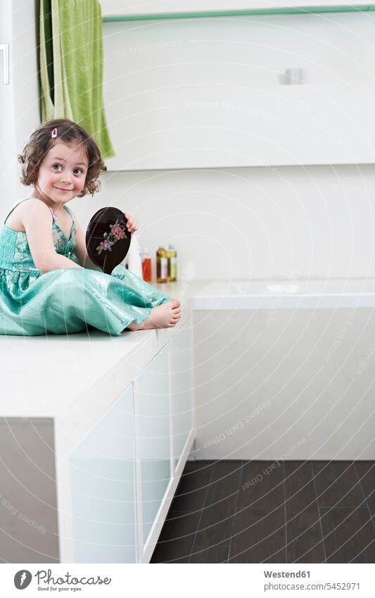Porträt eines lächelnden kleinen Mädchens mit Handspiegel im Badezimmer sitzend weiblich Portrait Porträts Portraits Kind Kinder Kids Mensch Menschen Leute