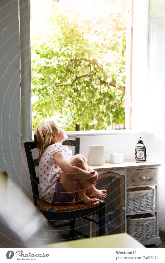 Kleines Mädchen sitzt auf einem Stuhl und schaut aus dem Fenster weiblich Kind Kinder Kids Mensch Menschen Leute People Personen beobachten zuschauen ansehen