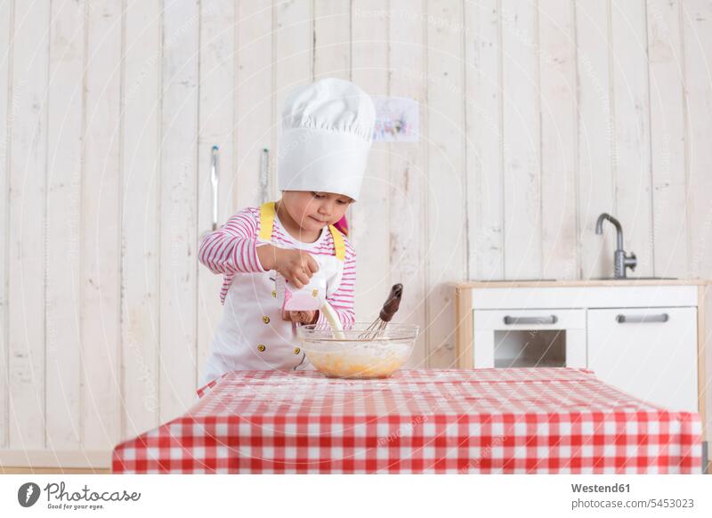 Kleines Mädchen, das Waffeln zubereitet und eine Kochmütze trägt Küche weiblich backen Teig stehen stehend steht Kind Kinder Kids Mensch Menschen Leute People