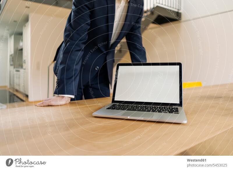 Geschäftsmann mit Laptop auf Tisch gelehnt Büro Office Büros Notebook Laptops Notebooks Businessmann Businessmänner Geschäftsmänner Arbeitsplatz Arbeitsstätte