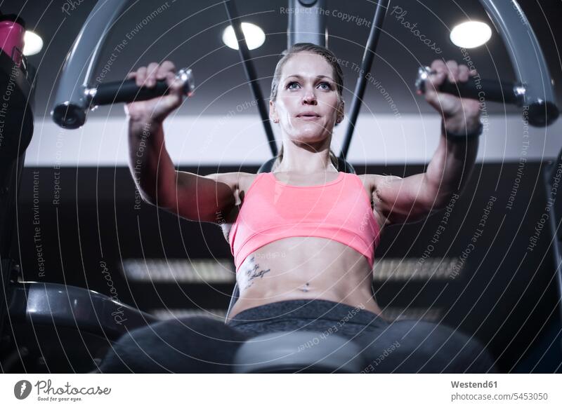 Fokussierte Frau mit Brust-Übungsgeräten im Fitness-Studio weiblich Frauen Fitnessstudio Fitnessclubs Fitnessstudios Turnhalle Erwachsener erwachsen Mensch