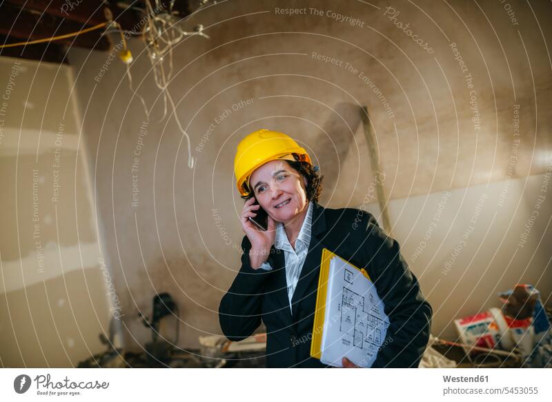 Frau mit Schutzhelm telefoniert auf einer Baustelle telefonieren anrufen Anruf telephonieren Handy Mobiltelefon Handies Handys Mobiltelefone Baustellen weiblich