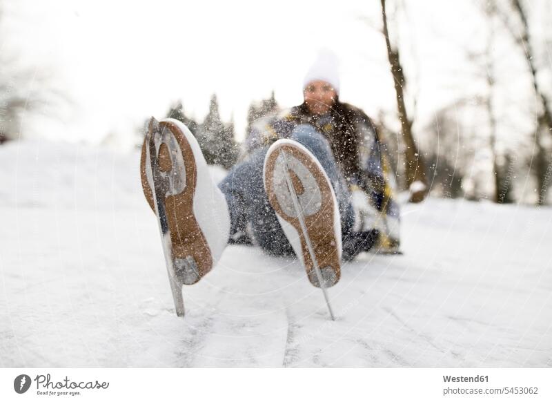 Frau mit Schlittschuhen auf Schnee liegend Schlittschuhlaufen Eislaufen lachen weiblich Frauen Spaß Spass Späße spassig Spässe spaßig liegt Winter winterlich