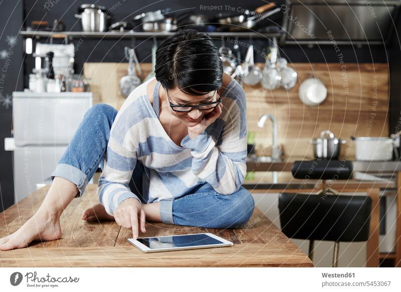 Frau sitzt am Tisch in der Küche und schaut auf die Tafel Tablet Tablet Computer Tablet-PC Tablet PC iPad Tablet-Computer weiblich Frauen Rechner Erwachsener