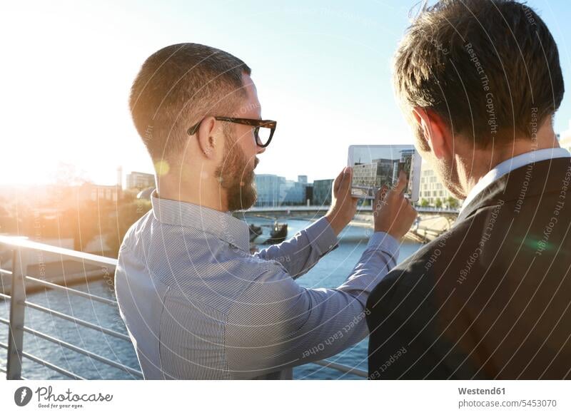 Zwei Geschäftsleute beim Fotografieren mit einer Tablette auf einer Brücke in der Stadt sprechen reden Tablet Computer Tablet-PC Tablet PC iPad Tablet-Computer