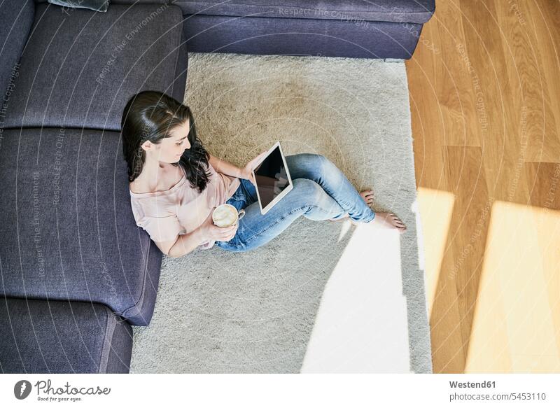 Junge Frau benutzt Tablette zu Hause im Wohnzimmer Tablet Computer Tablet-PC Tablet PC iPad Tablet-Computer weiblich Frauen Rechner Erwachsener erwachsen Mensch