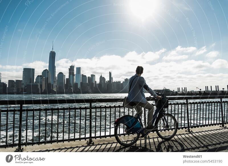 USA, Mann auf dem Fahrrad am Hafen von New Jersey mit Blick auf Manhattan fahren fahrend fahrender fahrendes New York New York State Bikes Fahrräder Räder Rad