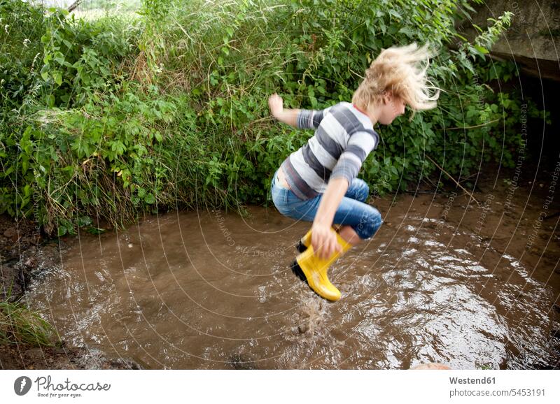 Aufgeregtes Mädchen springt in den Bach Spaß Spass Späße spassig Spässe spaßig springen hüpfen Bäche Baeche weiblich Sprung Spruenge Sprünge Gewässer Wasser