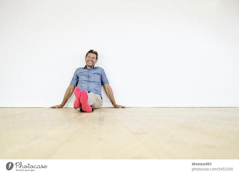 Erwachsener Mann sitzt auf dem Boden in leerem Raum Männer männlich Zuhause zu Hause daheim nachdenken überlegen auf dem Boden sitzen auf dem Boden sitzend