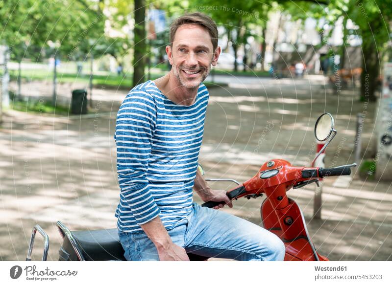 Porträt eines lächelnden reifen Mannes mit Motorroller Roller Piaggio Männer männlich Portrait Porträts Portraits Kraftfahrzeug Verkehrsmittel KFZ Erwachsener