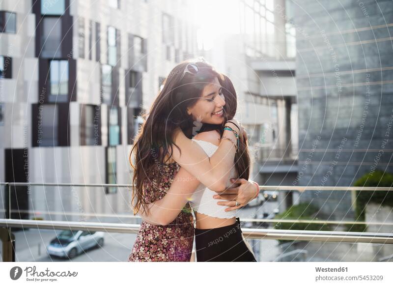 Zwei glückliche junge Frauen umarmen sich in der Stadt Freundinnen lächeln Umarmung Umarmungen Arm umlegen Freunde Freundschaft Kameradschaft Glück