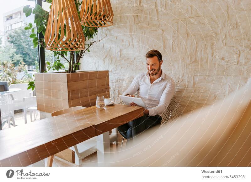 Lächelnder Mann mit Tablette in einem Cafe Geschäftsmann Businessmann Businessmänner Geschäftsmänner Kaffeehaus Bistro Cafes Café Cafés Kaffeehäuser