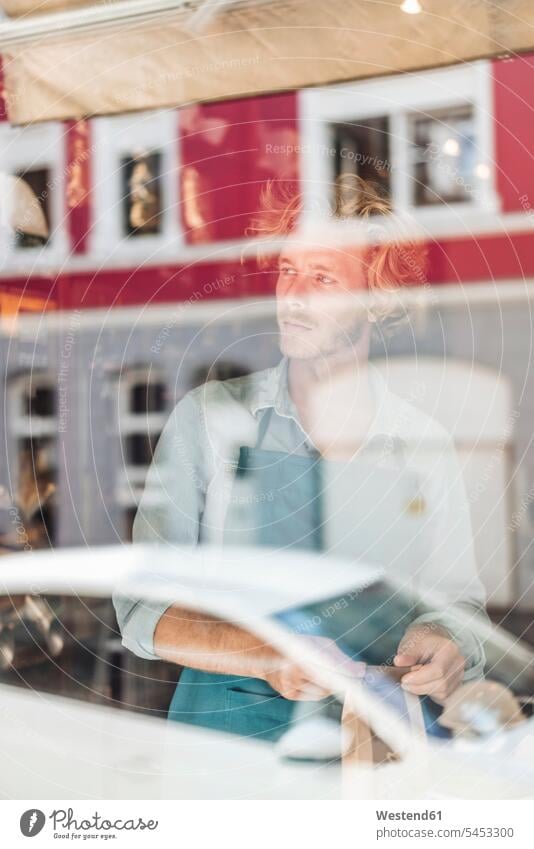Kaffeeröster in seinem Geschäft hinter der Fensterscheibe denken nachdenken verpacken Portrait Porträts Portraits Shop Laden Läden Geschäfte Shops Mann Männer