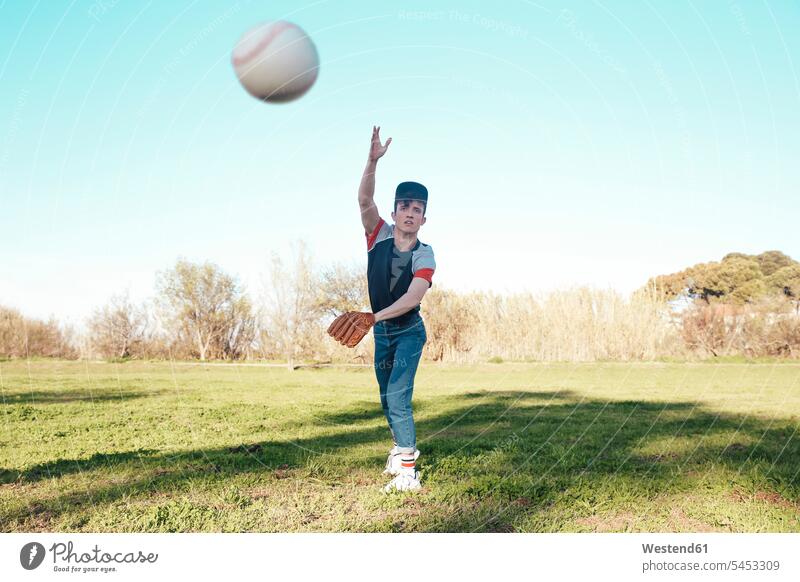 Junger Mann wirft einen Baseball im Park Männer männlich Ball Bälle werfen Wurf Baseballspiel Baseballspieler Baseballer Erwachsener erwachsen Mensch Menschen
