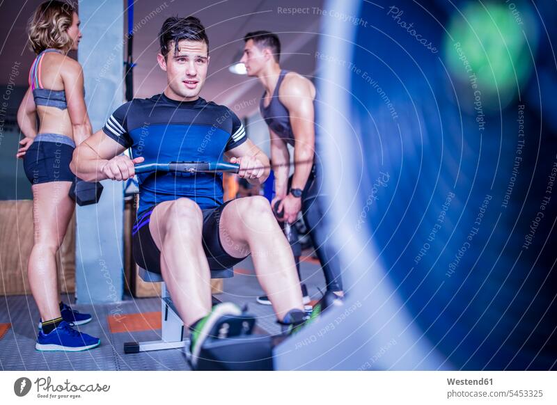 Junger Mann übt am Rudergerät im Fitnessstudio trainieren Fitnessclubs Fitnessstudios Turnhalle Männer männlich fit Gesundheit gesund Sport Erwachsener
