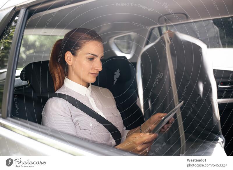 Geschäftsfrau, die auf dem Rücksitz eines Autos sitzt und ein Tablett benutzt Tablet Computer Tablet-PC Tablet PC iPad Tablet-Computer Wagen PKWs Automobil