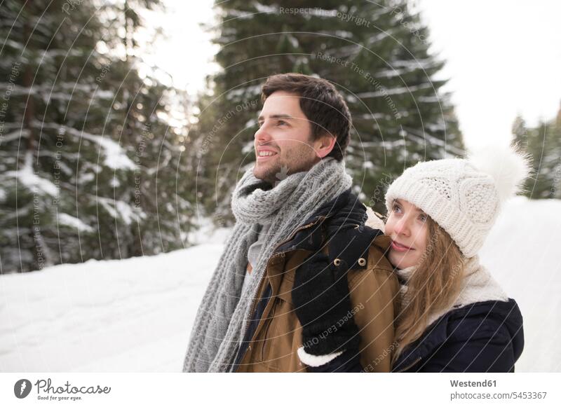 Glückliches junges Paar im schneebedeckten Winterwald Schnee Pärchen Paare Partnerschaft Wetter Mensch Menschen Leute People Personen genießen geniessen Genuss