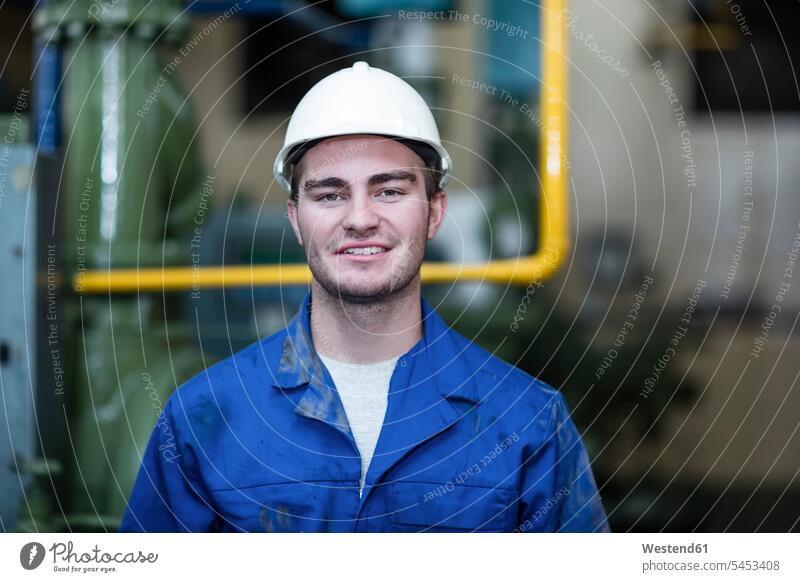 Porträt eines selbstbewussten Arbeiters in der Fabrik Helm Helme Portrait Porträts Portraits lächeln Job Mann Männer männlich Fabrikgebäude Fabrikgebaeude
