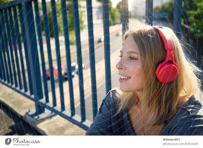 Porträt einer lächelnden jungen Frau, die mit Kopfhörern Musik hört Kopfhoerer weiblich Frauen hören hoeren Portrait Porträts Portraits Erwachsener erwachsen