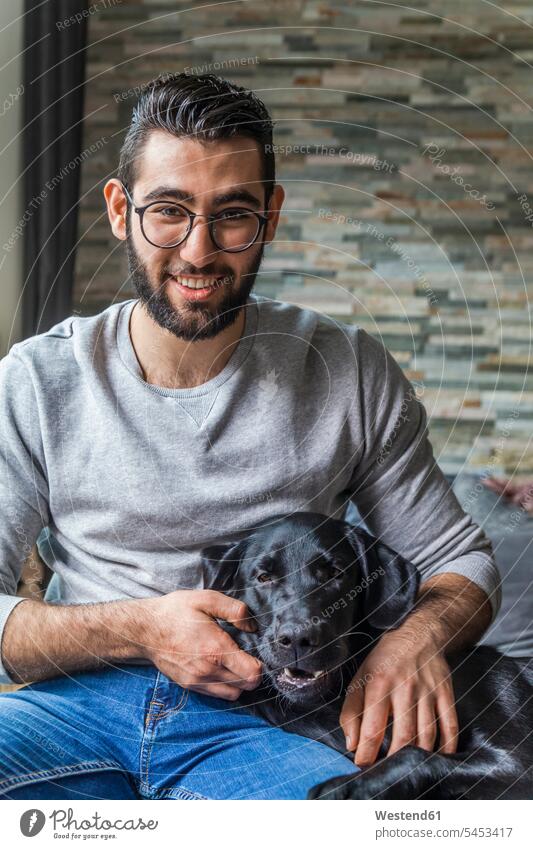 Porträt eines lächelnden jungen Mannes mit seinem Hund zu Hause Hunde Portrait Porträts Portraits Männer männlich Haustier Haustiere Tier Tierwelt Tiere
