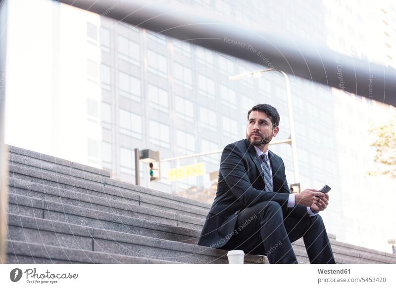 Geschäftsmann sitzt auf der Treppe mit Handy und Kaffee zum Mitnehmen Mobiltelefon Handies Handys Mobiltelefone Pause Businessmann Businessmänner