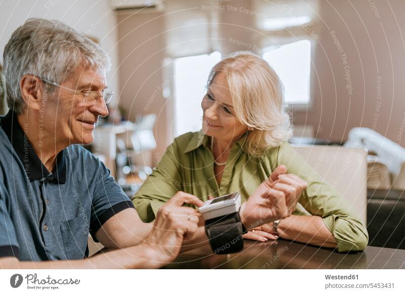 Lächelndes älteres Paar bei der Blutdruckmessung Senior ältere Männer älterer Mann Senioren lächeln Pärchen Paare Partnerschaft Krankheit Erkrankungen