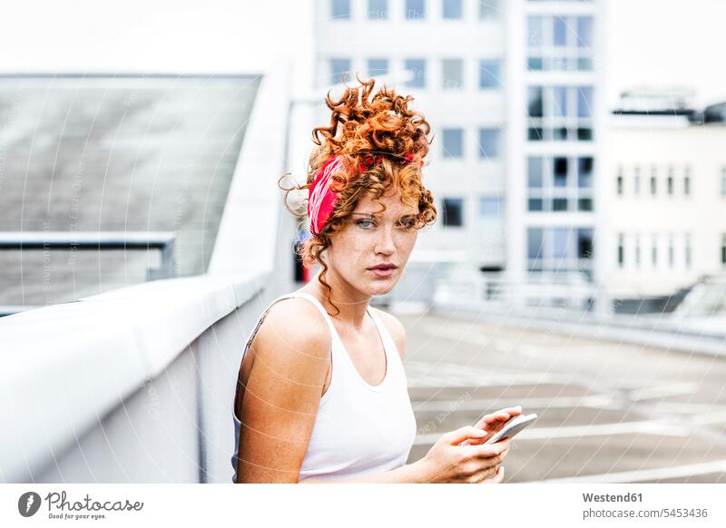 Porträt einer rothaarigen Frau mit Handy in der Hand Portrait Porträts Portraits Mobiltelefon Handies Handys Mobiltelefone Locken lockiges Haar gelockt