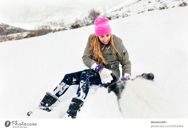 Junge Frau spielt mit ihrem Hund im Schnee tierlieb Tierliebe spielen Hunde lachen Winter winterlich Winterzeit Tierfreund tierfreundlich Tierfreundschaft