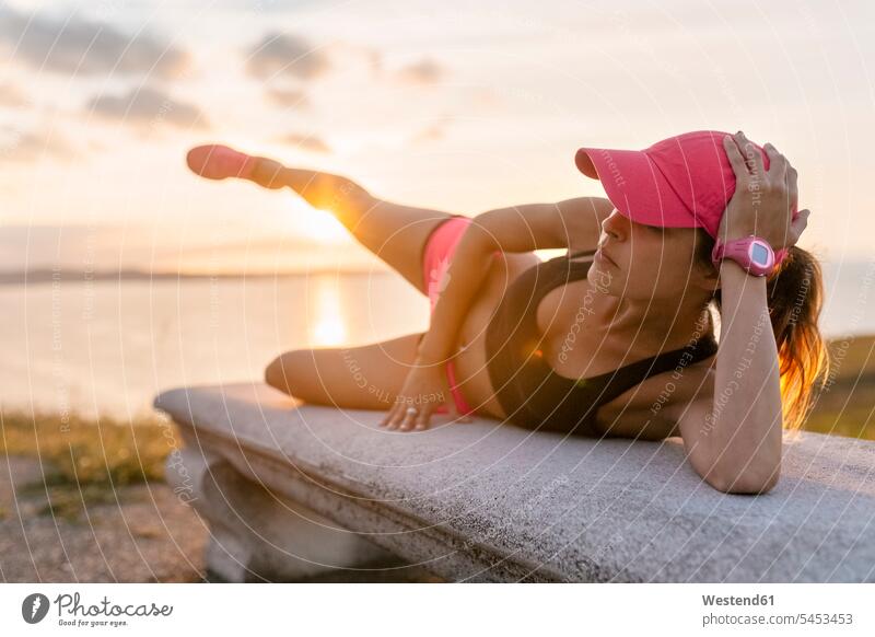 Junge Frau beim Krafttraining auf einer Bank am Meer Sitzbänke Bänke Sitzbank aufwärmen sich aufwärmen sich aufwaermen stark Stärke kräftig Side-Plank