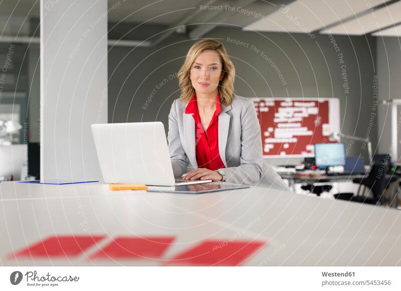 Porträt einer selbstbewussten Geschäftsfrau mit Laptop im Büro Notebook Laptops Notebooks Office Büros Geschäftsfrauen Businesswomen Businessfrauen