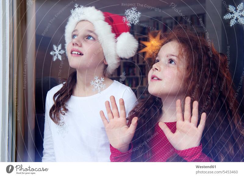 Kleine Mädchen stehen am Fenster und warten auf Weihnachten Christmas X-Mas X mas Erwartung erwartungsvoll erwarten Vorfreude staunen erstaunen Schwester