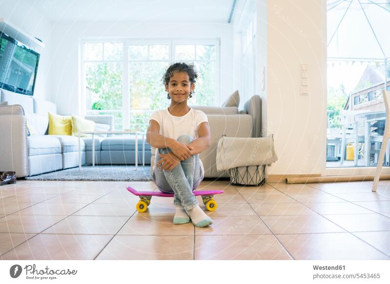 Kleines Mädchen sitzt auf einem Skateboard und schaut stolz sitzen sitzend Rollbretter Skateboards weiblich Wohnzimmer Wohnraum Wohnung Wohnen Wohnräume