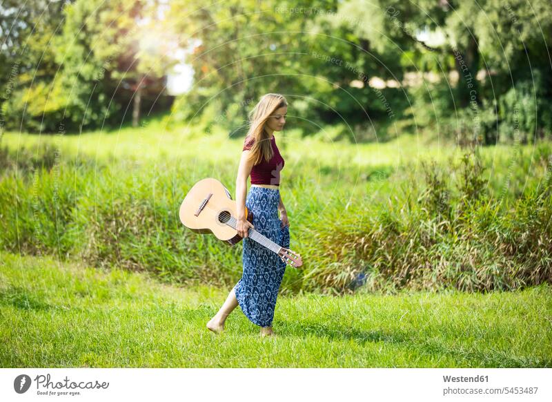 Junger Woan in der Natur mit Gitarre gehen gehend geht Gras Gräser Graeser romantisch schwärmerisch schwaermerisch gefuehlvoll gefühlvoll Romantik Gitarren