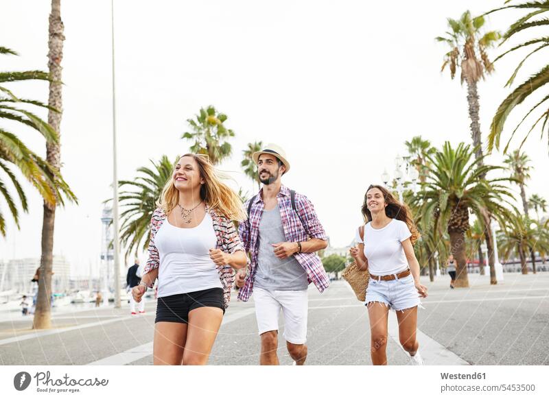 Spanien, Barcelona, drei Touristen, die in der Stadt unterwegs sind lächeln Freunde rennen Tourismus Freundschaft Kameradschaft Freizeit Muße glücklich Glück